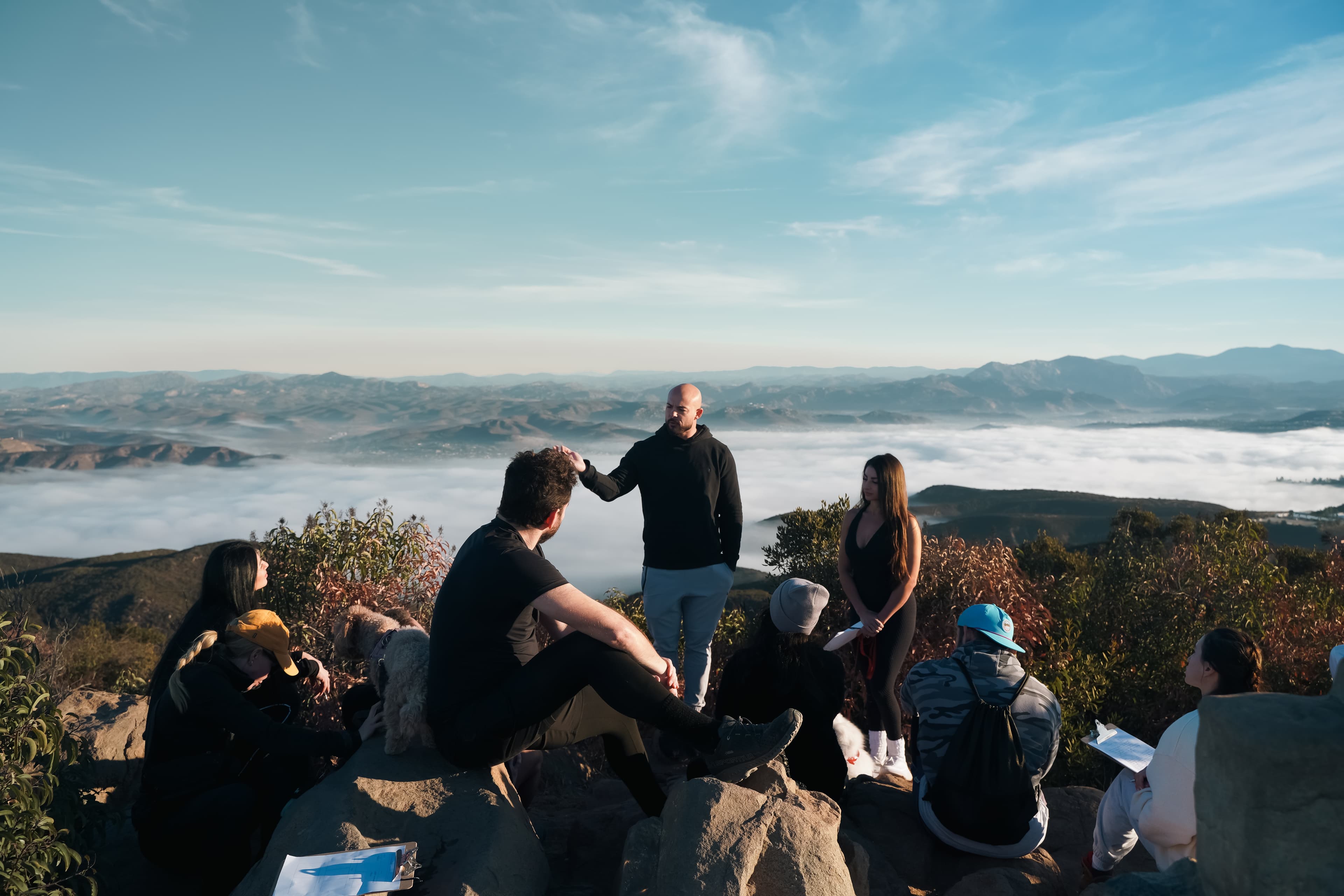 Garin speaking to a group on a mountaintop above the clouds