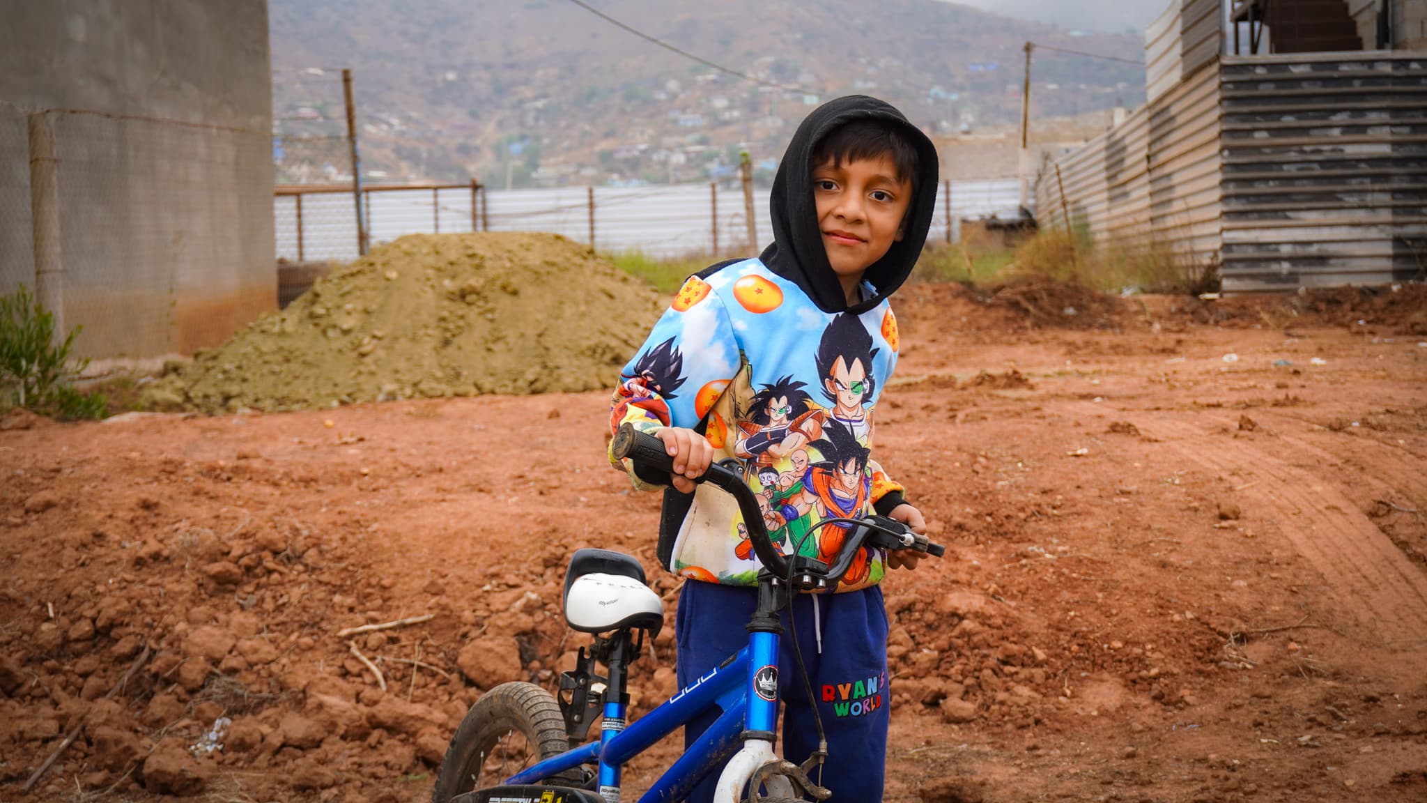 The young son of the Pérez Vázquez family on his bike at the build site, Ensenada hills in the background