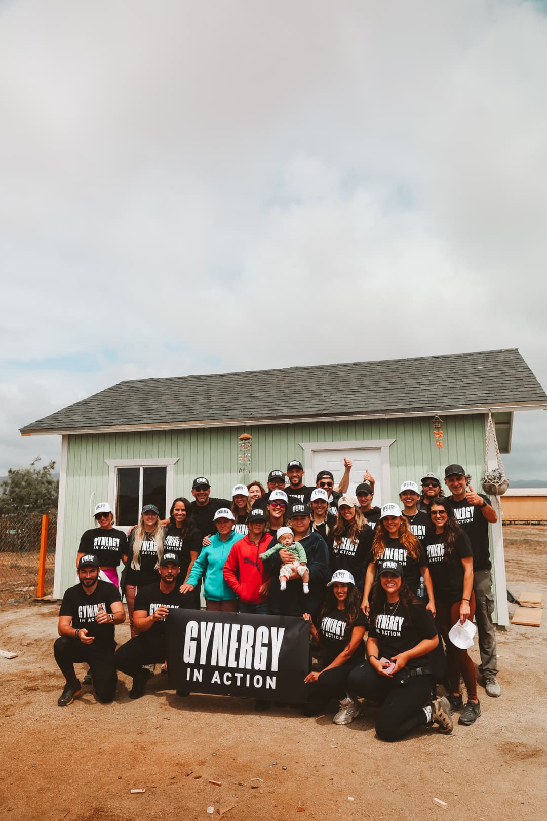 GYNERGY In Action full group with banner at completed home build